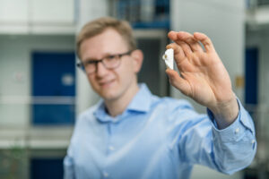 Engineer presenting a 3D-printed ceramic extrusion insert made from high-purity aluminum oxide (Al₂O₃), showcasing the precision of additive manufacturing in brick tooling applications.