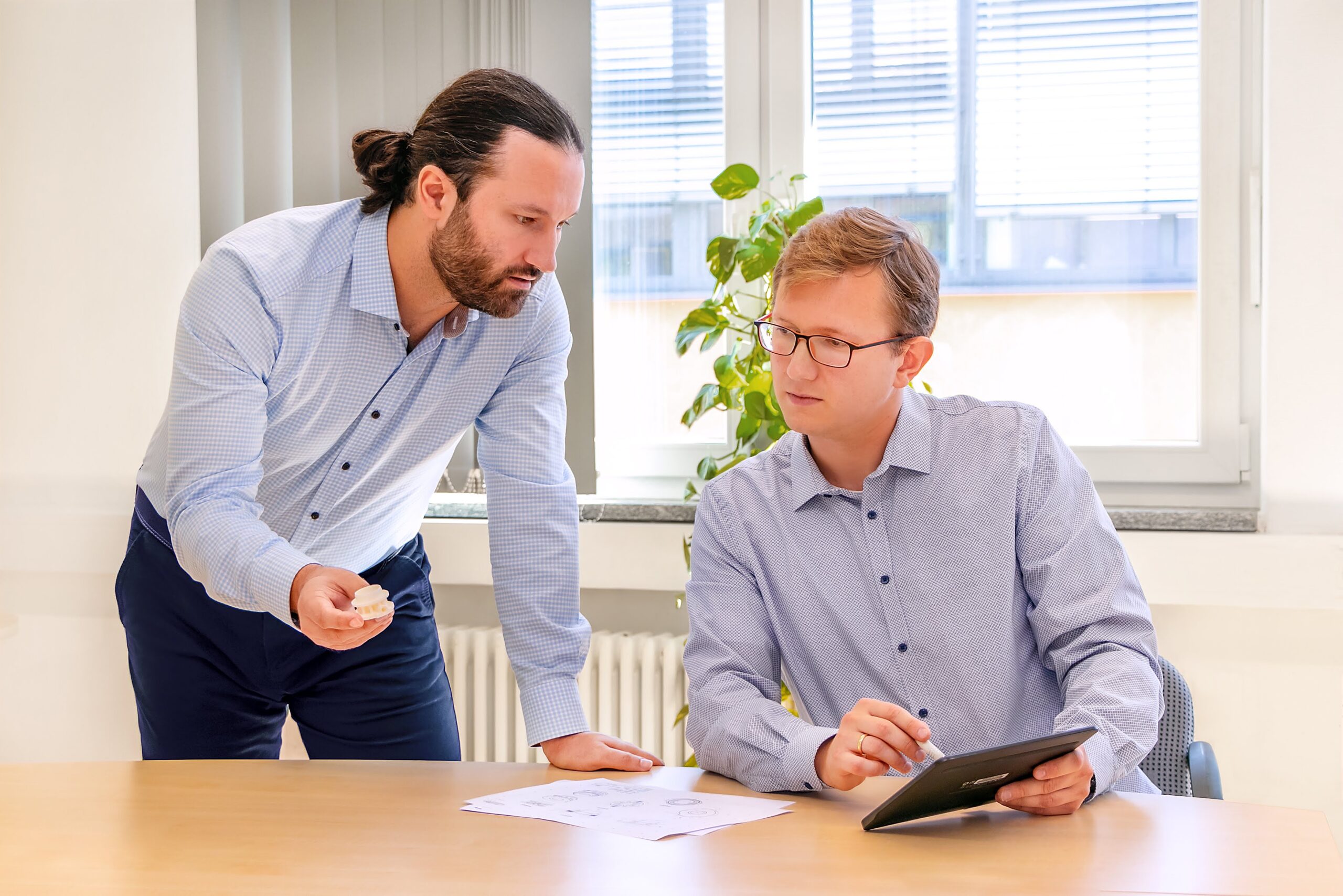 Two Hilgenberg Ceramics engineers reviewing a ceramic part prototype and CAD drawings at a desk