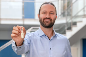 A person holding a compact, 3D-printed ceramic crucible made of high-purity alumina, designed for high-temperature analysis